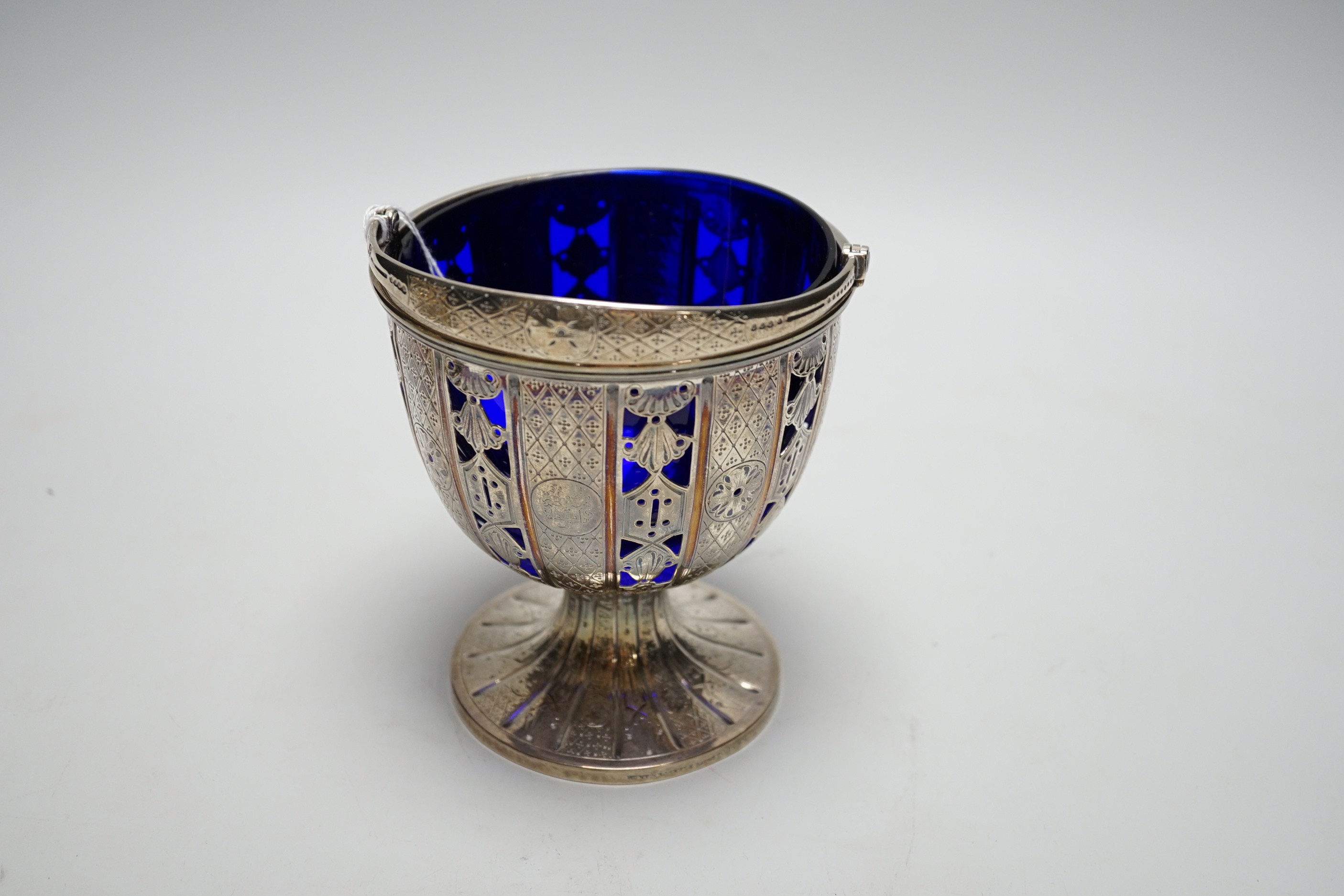 A Victorian pierced silver pedestal sugar basket, by John Samuel Hunt, London, 1859, with blue glass liner, height 13.1cm excluding handle, 12.4oz.